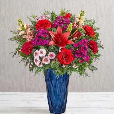 Create a dazzling yuletide display with our luxury arrangement. Inspired by the elegance of the Victorian era, it’s filled with a gathering of jewel tone blooms in our Blue Harmony vase, which enhances its beauty with striking color and exquisite texture. As a gift or part of the décor, this bouquet captures the beauty of the holiday season in every last detail.