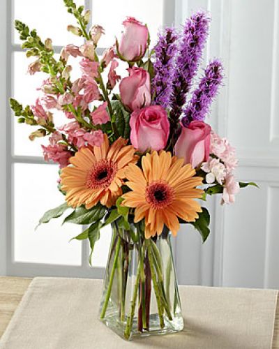 <p>Exuding a special charm, with a casual fresh-from-the-garden look, this gorgeous spring bouquet is the perfect way to delight your recipient in honor of any of life's most treasured moments. Peach gerbera daisies are soft and sophisticated surrounded by pink roses, pink snapdragons, pink mini carnations, purple liatris, and lush greens arranged with an artist's eye in a gathered square clear glass vase.</p>