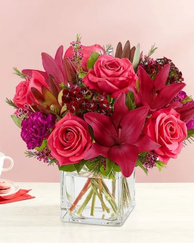 <p>Radiant jewel tones set the tone for a romantic Valentine’s Day. Our eye-catching arrangement mixes classic roses and lilies with unique Leucadendron and dianthus. Gathered in a chic cube vase with lush touches of greenery, it’s a sweet and stylish expression of love.</p>