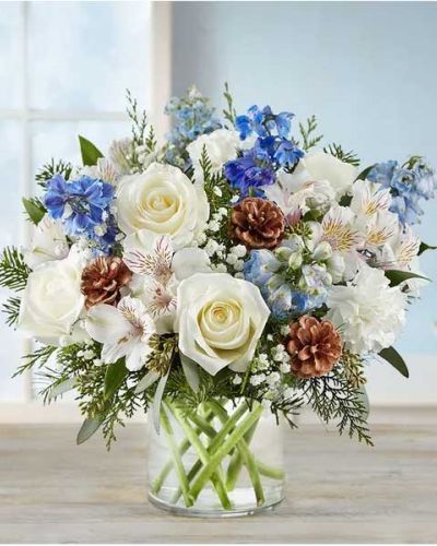 Inspired by winter’s cool blue & white landscape, our delightful arrangement delivers warm wishes to the people you love. Hand-designed with a lush gathering of blooms, evergreens and rustic touches, it’s a thoughtful sentiment filled with the season’s natural beauty.
<ul>
<li>All-around arrangement with white roses, carnations and Peruvian lilies (alstroemeria); blue delphinium; accented with baby’s breath, seeded eucalyptus, assorted Christmas greenery and pinecones</li>
<li>Artistically designed in a clear glass cylinder vase</li>
<li>Large arrangement measures approximately 15"H x 13"W</li>
<li>Medium arrangement measures approximately 13"H x 12"W</li>
<li>Small arrangement measures approximately 12"H x 9"W</li>
<li>Our florists hand-design each arrangement, so colors, varieties and container may vary due to local availability</li>
<li>To ensure lasting beauty, Peruvian lilies may arrive in bud form and will fully bloom over the next few days</li>
</ul>